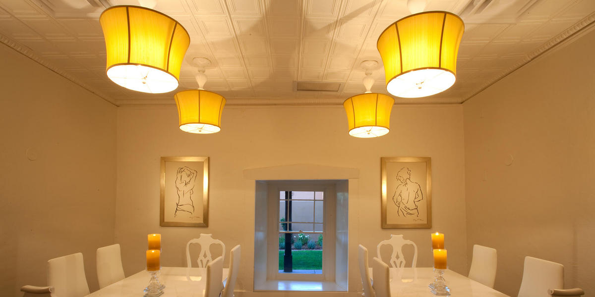 Table in Casa Esencia with white chairs and upside down lamps on ceiling