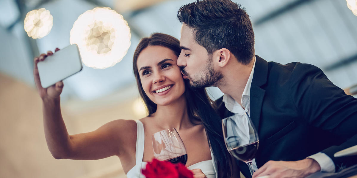COUPLE TAKING SELFIE WITH WINE AND ROSES